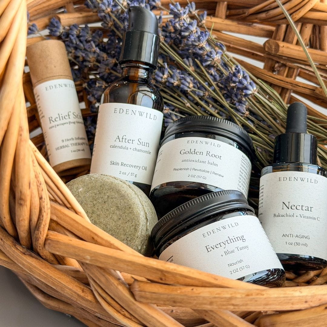 Edenwild natural skincare product collection in a wicker basket — After Sun oil, Golden Root tallow balm, Everything Balm, Nectar facial serum, and Relief Stick, formulated and made by Edenwild, a Wyoming-based ancestral skincare brand