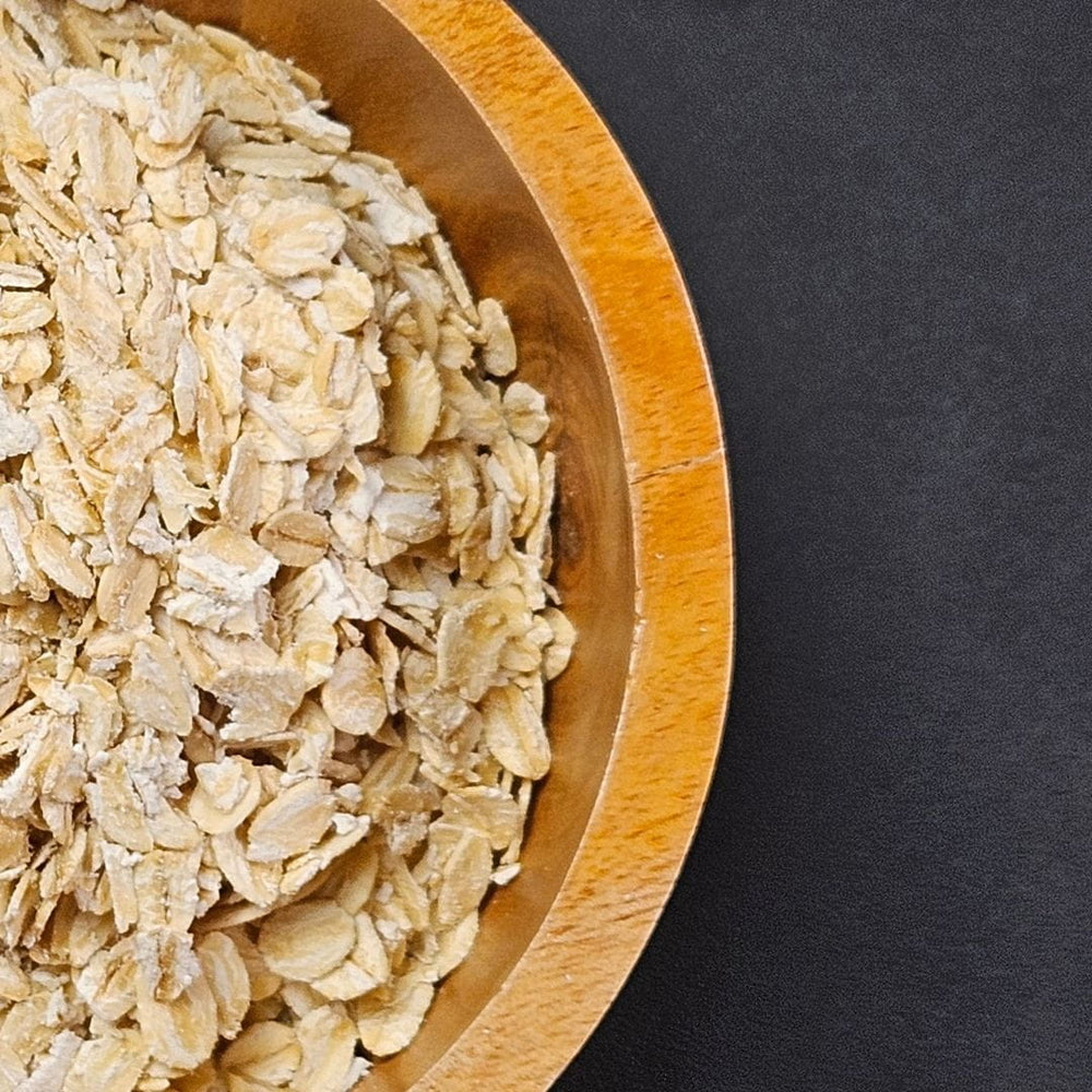 Close-up of rolled oats in a wooden bowl, representing oatmeal used in Edenwild Happy Baby balm to help soothe dry, sensitive skin.