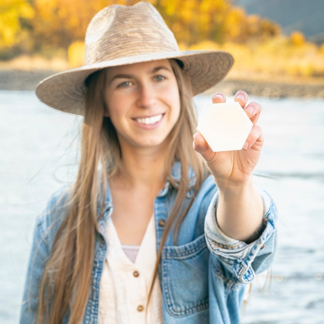 Woman holding Edenwild Aire solid conditioner bar outdoors — plant-based conditioner bar for smooth, frizz-free, and moisturized hair