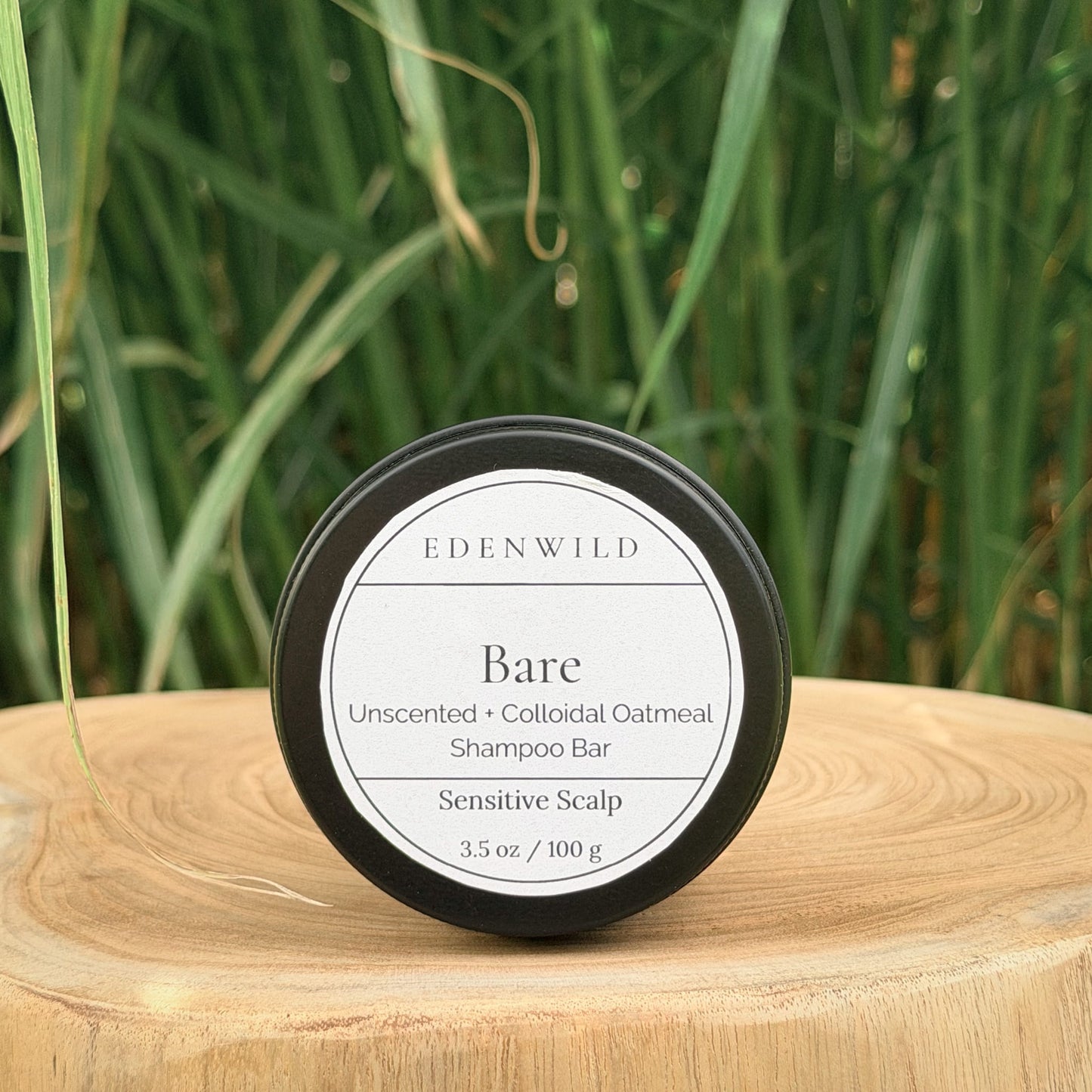 Edenwild Bare Shampoo Bar on wood stump pedestal with natural grass background — unscented colloidal oatmeal shampoo bar for sensitive scalp, fragrance-free and sulfate-free