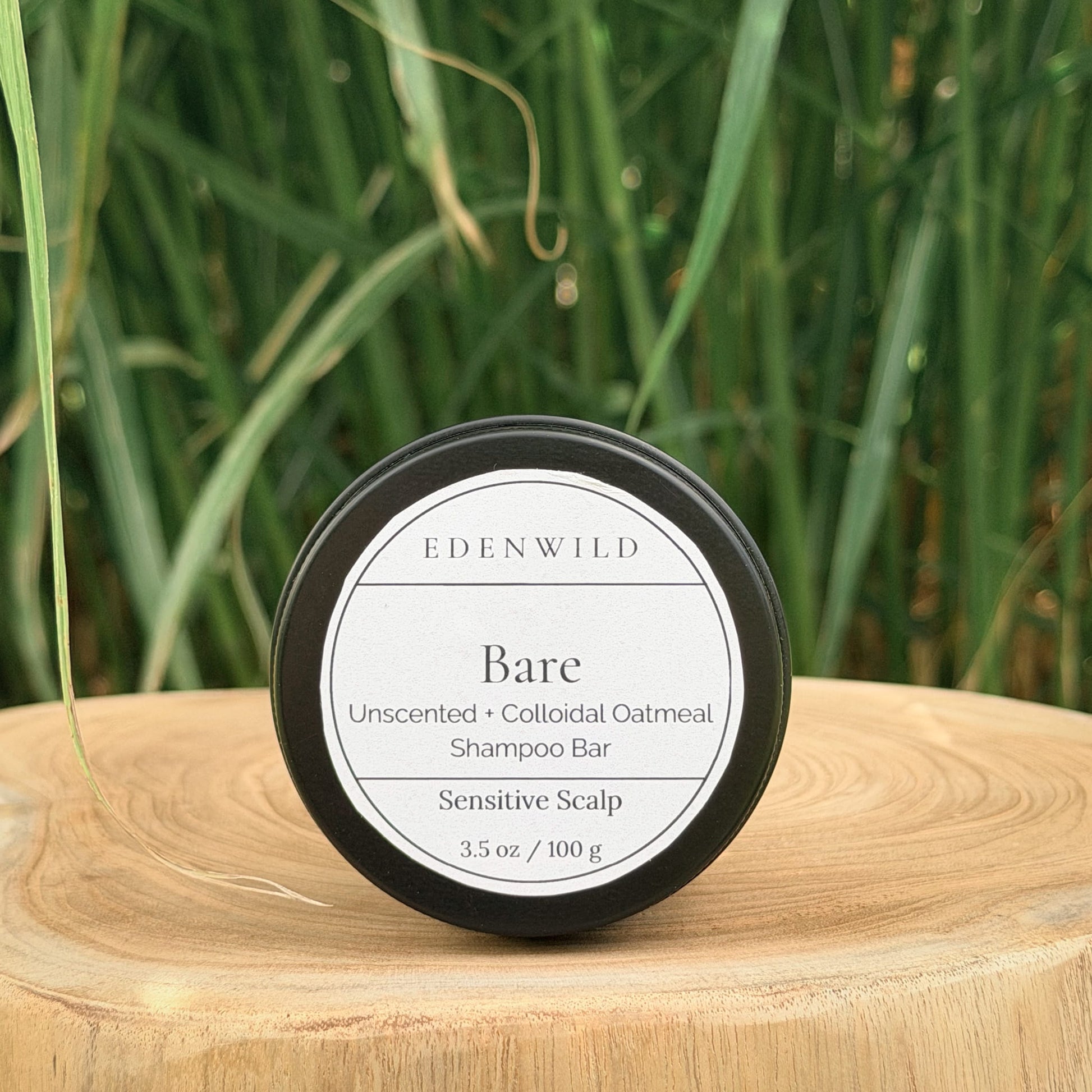 Edenwild Bare Shampoo Bar on wood stump pedestal with natural grass background — unscented colloidal oatmeal shampoo bar for sensitive scalp, fragrance-free and sulfate-free