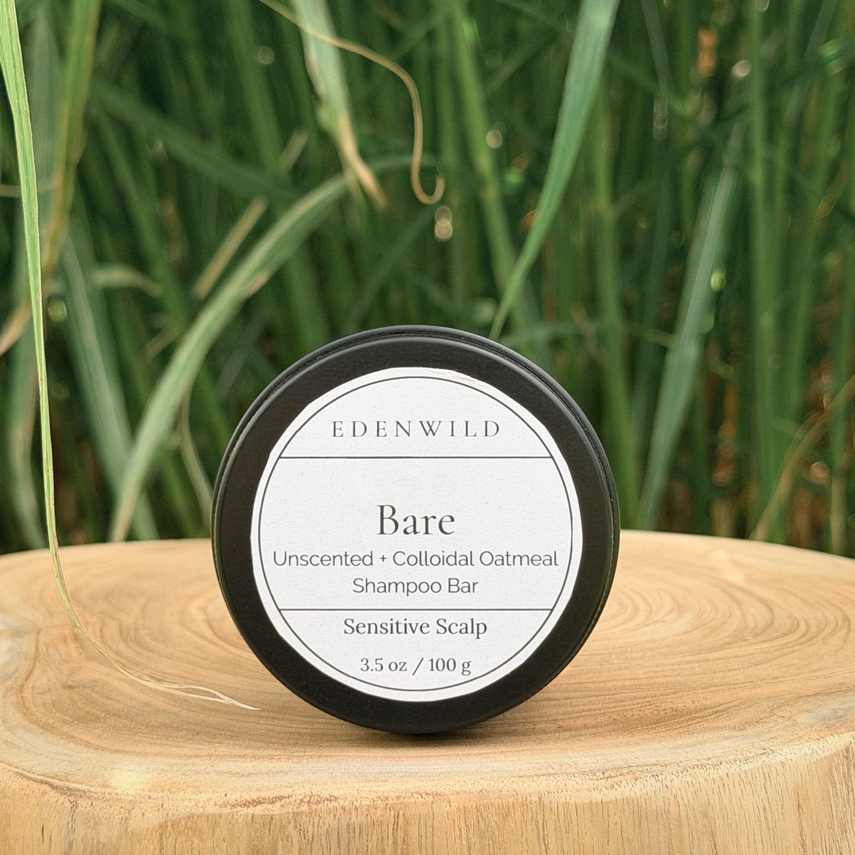 Edenwild Bare Shampoo Bar on wood stump pedestal with natural grass background — unscented colloidal oatmeal shampoo bar for sensitive scalp, fragrance-free and sulfate-free