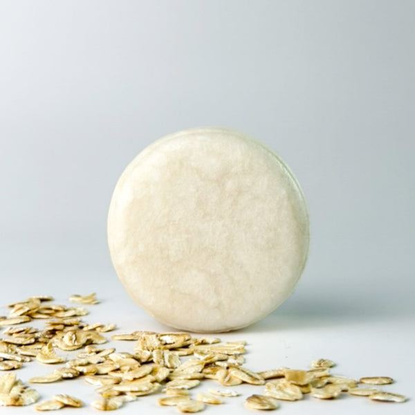 Edenwild Bare Shampoo Bar with colloidal oatmeal on grey background surrounded by rolled oats — unscented natural shampoo bar for sensitive scalp and eczema