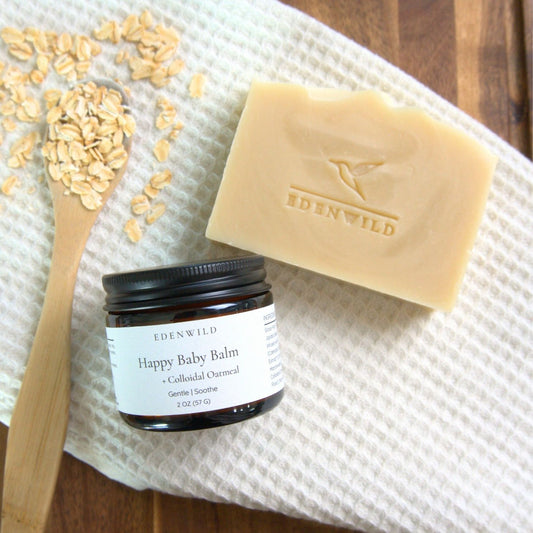 Flat lay of Happy Baby Balm and Happy Baby Soap with colloidal oatmeal on wooden spoon used in Edenwild Gentle Skin Duo to help soothe eczema and sensitive skin