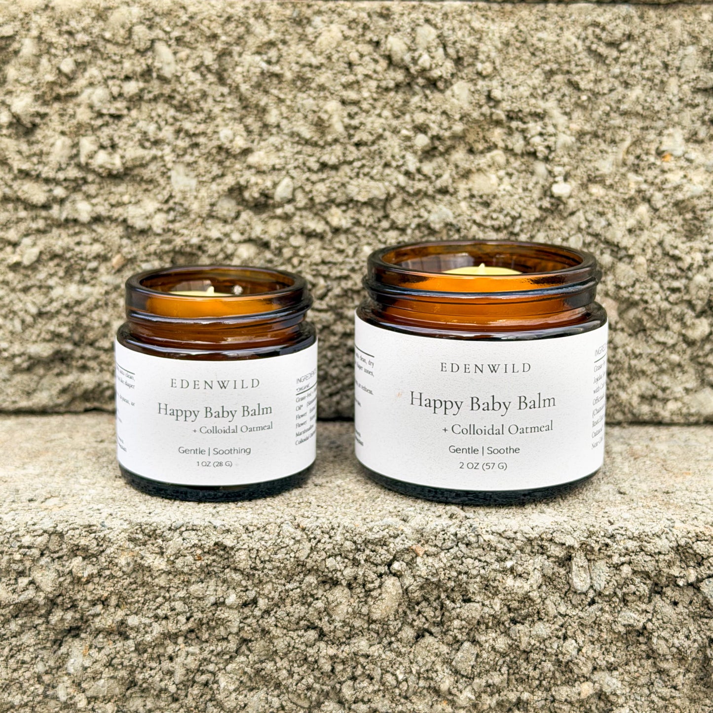 Edenwild Happy Baby Balm in two sizes on stone surface — natural colloidal oatmeal balm for eczema, sensitive skin, and newborn skin care