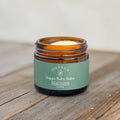 Open jar of Edenwild Happy Baby Tallow Balm, an ancestral skincare balm for delicate skin, with a sage green label on a rustic wooden surface.