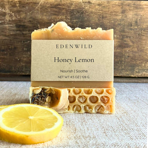 Edenwild Honey Lemon soap bar with cream label beside a fresh lemon slice on rustic wood — botanical bar soap to nourish and brighten skin