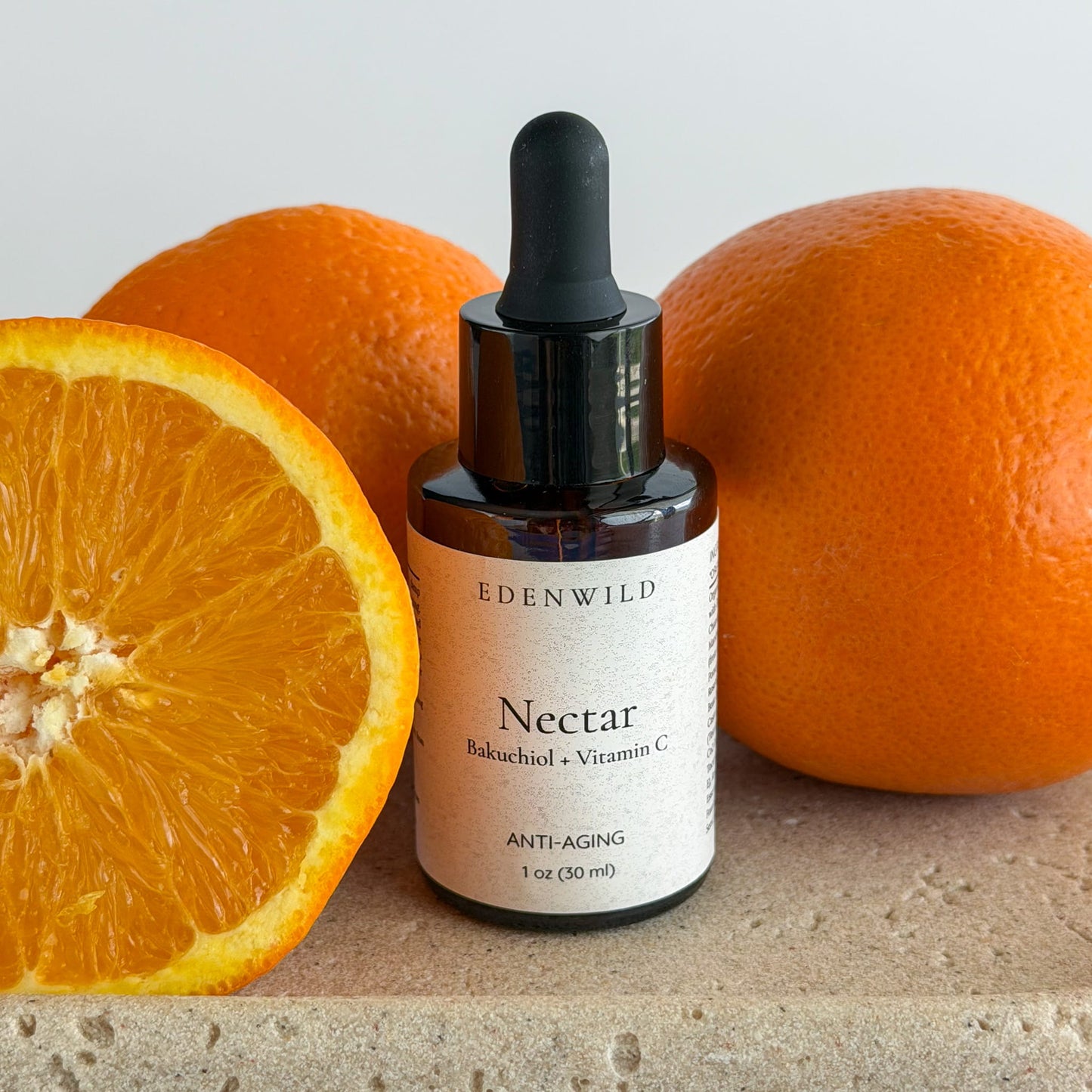 Edenwild Nectar bakuchiol and vitamin C face serum beside fresh oranges — natural retinol alternative serum for brightening and anti-aging
