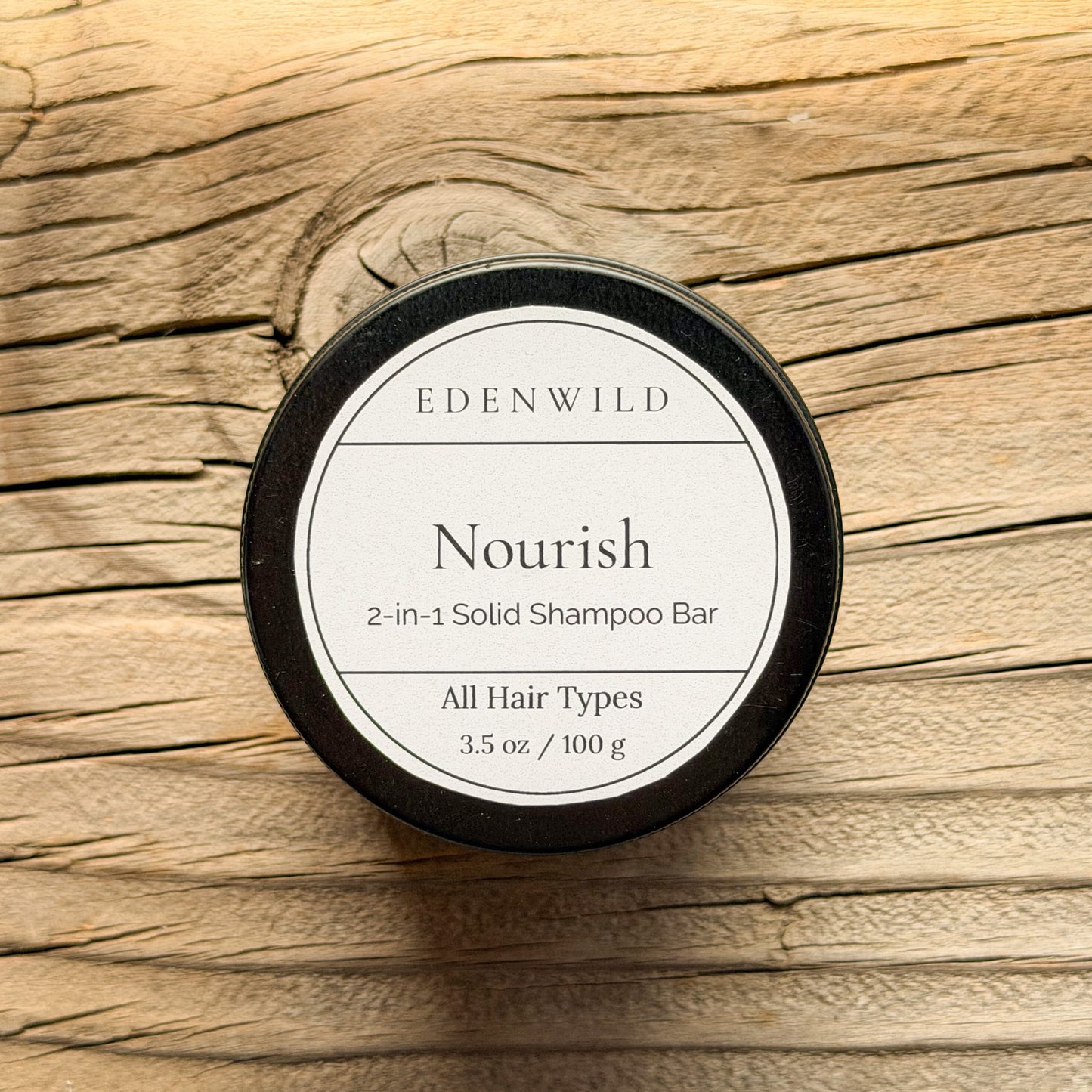 Edenwild Nourish 2-in-1 Solid Shampoo Bar for all hair types, 3.5 oz, in black tin on rustic wood background