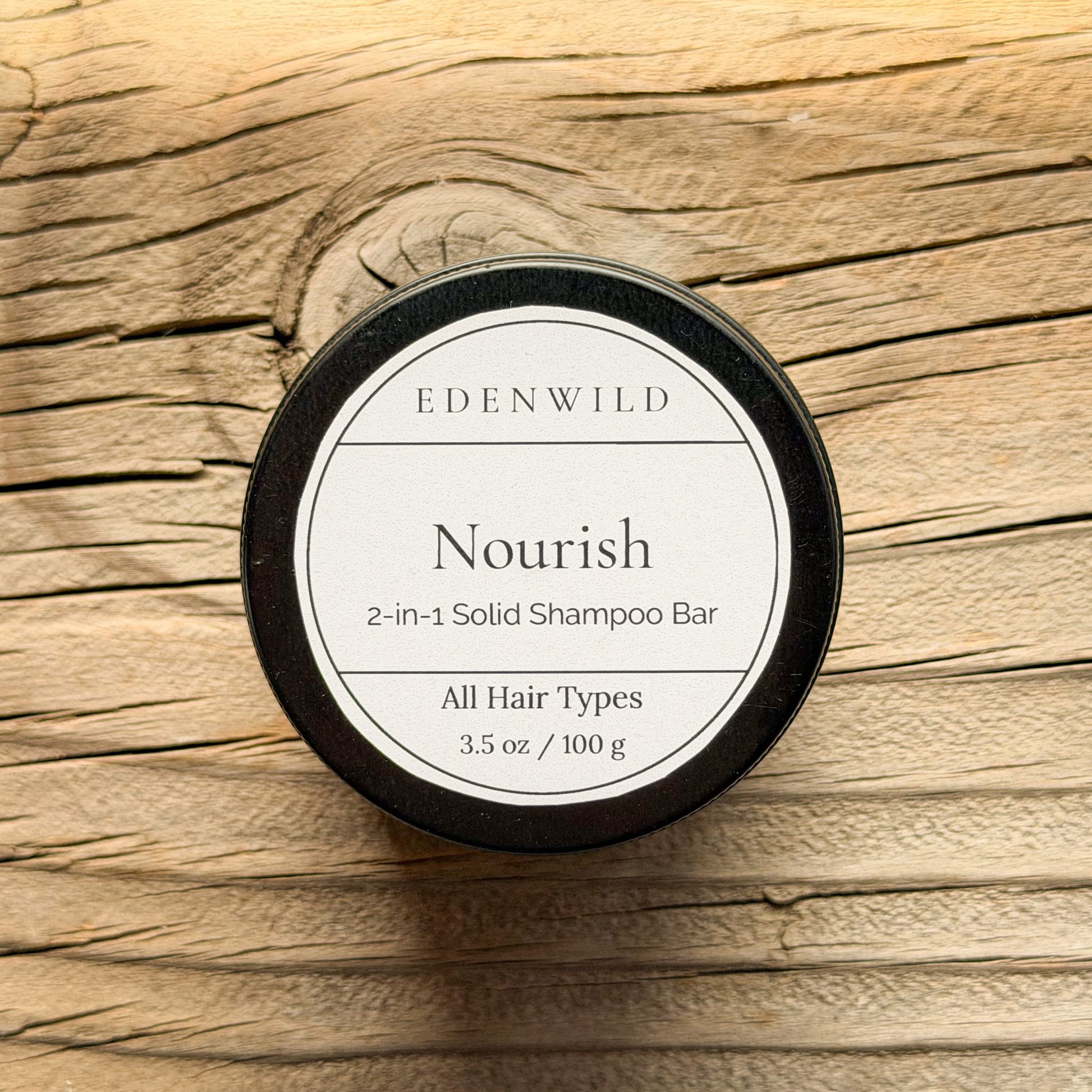 Edenwild Nourish 2-in-1 Solid Shampoo Bar for all hair types, 3.5 oz, in black tin on rustic wood background