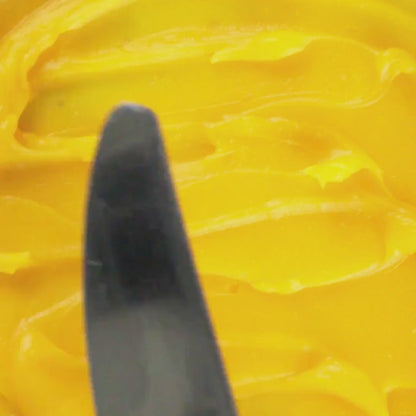 Spatula gliding through Edenwild's Golden Root grass-fed tallow balm with sea buckthorn, frankincense, and green coffee bean oil used to help calm inflammation and stressed skin
