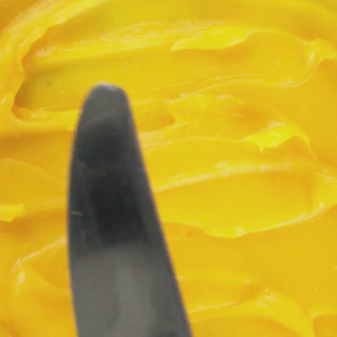 Spatula gliding through Edenwild's Golden Root grass-fed tallow balm with sea buckthorn, frankincense, and green coffee bean oil used to help calm inflammation and stressed skin