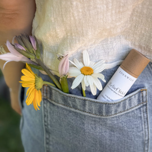 Edenwild Relief Stick herbal balm in denim pocket with wildflowers — natural plant-based remedy for cuts, bug bites, minor scrapes, and dry skin