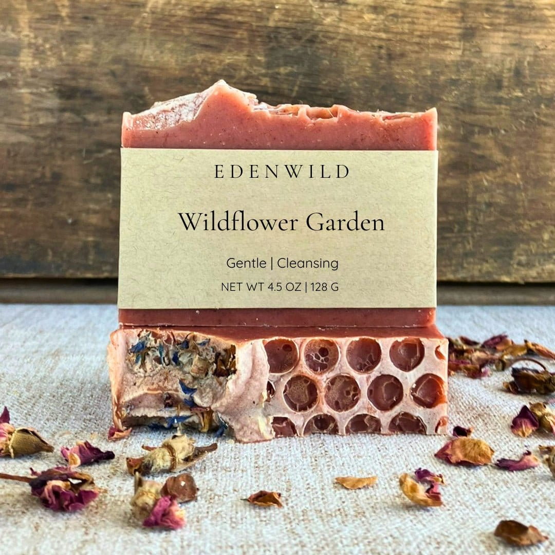 Edenwild Wildflower Garden natural soap bar surrounded by dried wildflowers and rose petals on a rustic wood background